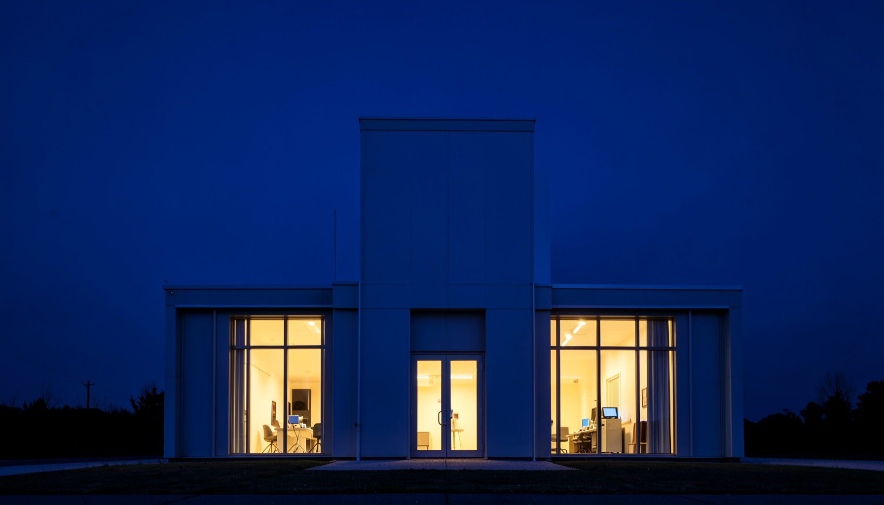 A clean architectural photograph of a modern weather station building at dusk, with deep navy sky and warm interior light spilling through large symmetrical windows, conveying a sense of calm scientific observation.